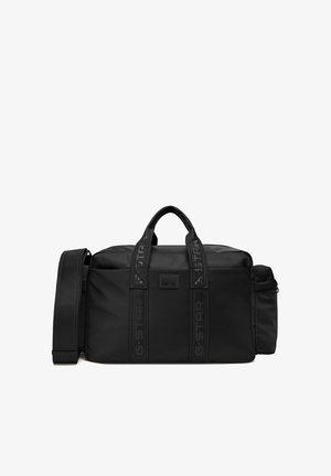 Czarna prostokątna torba sportowa z dwoma uchwytami, odpinanym paskiem na ramię, boczną kieszenią na zamek oraz logo G-STAR na paskach i przedniej naszywce.