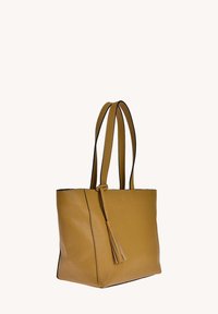 Sac fourre-tout en cuir jaune avec deux longues poignées, forme plate, surface texturée et un accent de pampille sur le côté.