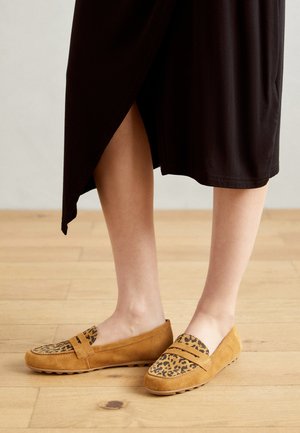 Tan ruskinds slip-on sko med en leopardmønster accent ved tåområdet, flad sål og subtile stiksyninger.