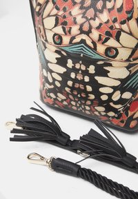 Borsa in pelle con un motivo di farfalle colorate e borchie dorate. Presenta dettagli con frange nere e hardware a clip.