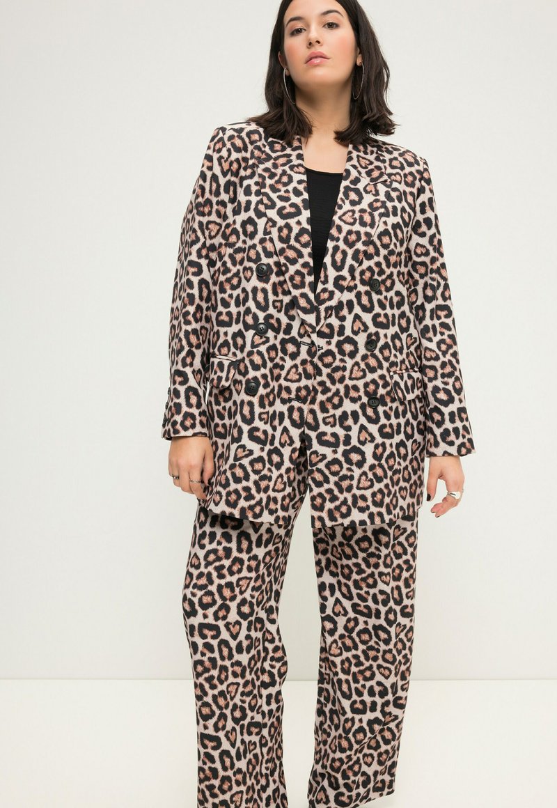 Leopardenprint pak in beige met zwarte en bruine vlekken. De dubbel-breasted blazer heeft grote knopen en de broek heeft een relaxte pasvorm.