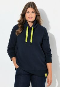 Marinblå pullover med strukturstickning, hög krage, gula mönstrade dragsnören och en gul logopatch vid nederkant. Långa ärmar.