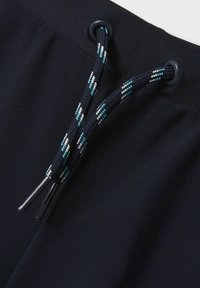 Zwarte zwembroek met een textuurstof, contrasterende geweven trekkoord in blauw, wit en zwart, en metalen oogjes voor bevestiging.