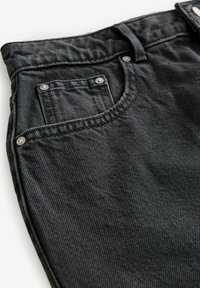 Sorte denim jeans med en textured finish, fem-lomme design og sølv hardware detaljer. Har en bred talje og bæltestropper.