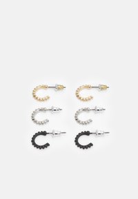 Conjunto de quatro brincos: dourados, prateados e pretos. Cada um tem uma forma curva com detalhes texturizados. Os materiais incluem metal e borracha.