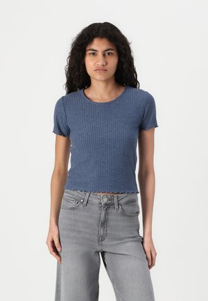 Blauw geribbeld T-shirt met korte mouwen, een ronde halslijn en een gegolfde zoom, gecombineerd met lichtgrijze jeans. De stof lijkt zacht en gestructureerd.