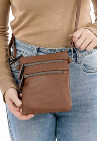 Borsa a tracolla in pelle marrone con tre tasche con zip, texture liscia, tracolla regolabile e logo impresso sulla parte inferiore.