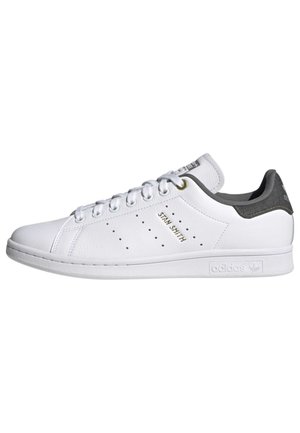 Witte Adidas Stan Smith-sneaker met geperforeerde strepen, gouden "Stan Smith"-tekst, witte veters en een donkergrijze hielkap.