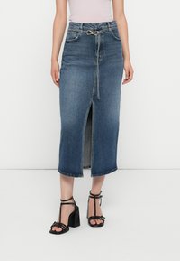 Denim maksi svārki ar priekšējo atvērumu, ar aukliņu vidukli un zeltīta apdare. Vidēja mazgāšanas zila krāsa ar nedaudz izbalējušu tekstūru.