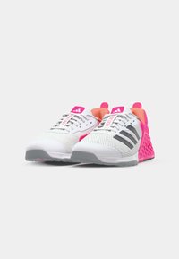 Scarpe da ginnastica bianche con accenti rosa e arancione, parte superiore in rete, suola grigia e tre strisce nere sui lati. Il testo sulla linguetta recita "HEATRON".