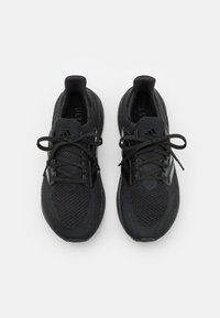 Baskets de sport noires avec une tige en tricot, bout arrondi et lacets. Présentent un design texturé et une semelle rembourrée pour le confort.