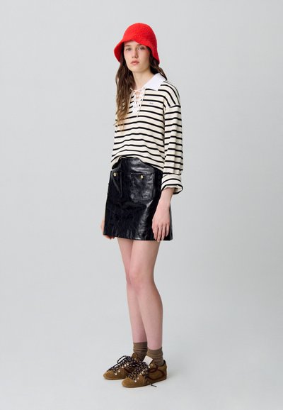 Camisa de manga larga a rayas con collar blanco; falda mini de cuero negra con bolsillos frontales; sombrero de cubo de lana roja; zapatillas marrones con cordones.