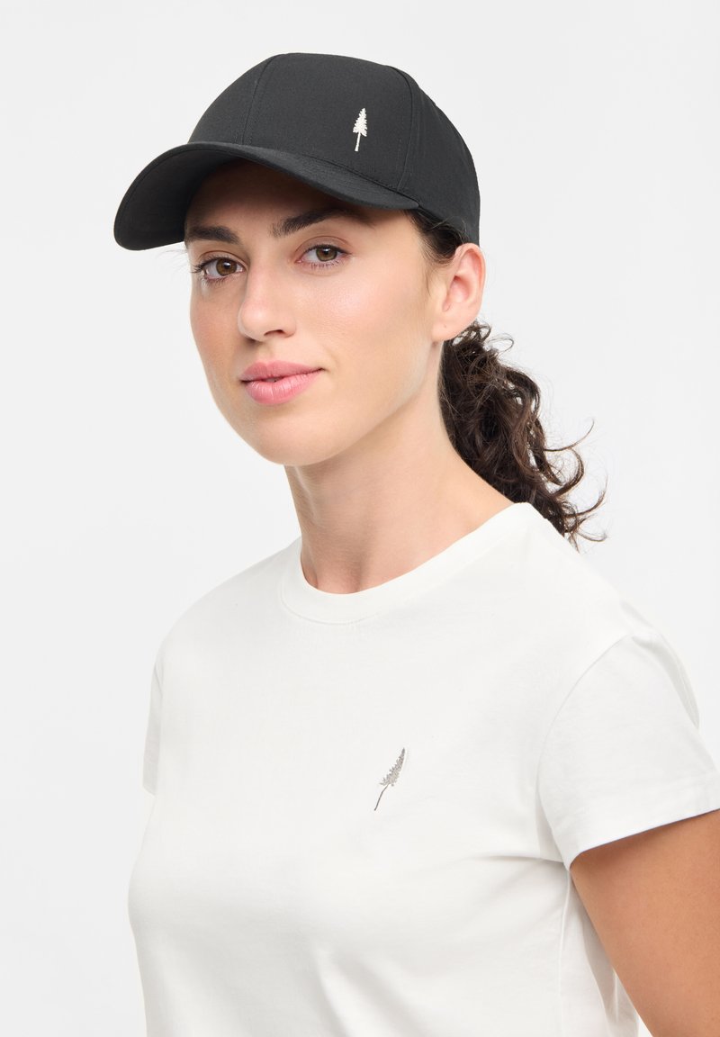 Black cap with a curved brim and a white embroidered tree logo, worn with a white t-shirt featuring a small embroidered design on the left side.