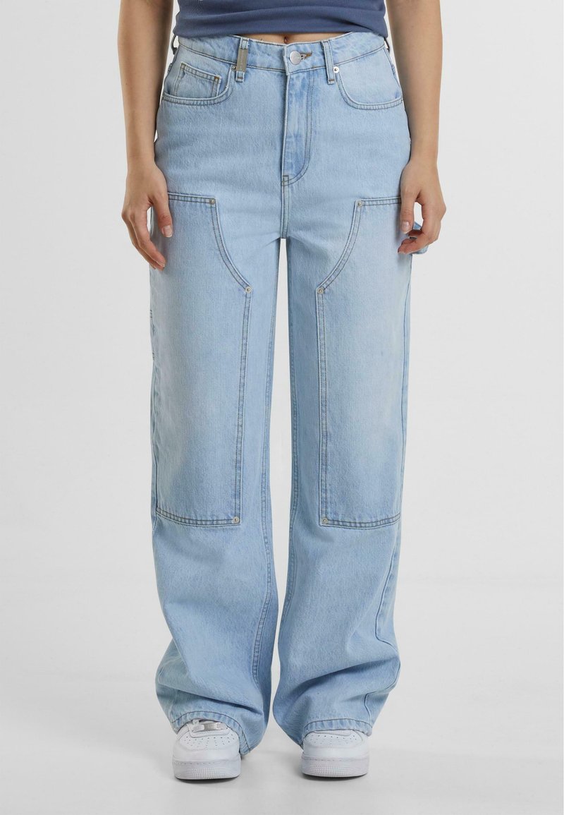 Svetlo modri široki jeans hlače imajo velike sprednje žepe, visok pas in sproščen fit z vidnimi šivi in nitmi.