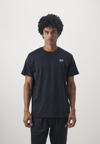 Schwarzes Baumwoll-T-Shirt mit Rundhalsausschnitt und kurzen Ärmeln, das ein kleines graues Logo auf der Brust und einen lässigen Schnitt bietet.