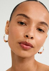 Gold hoop earrings adorned with pastel-colored beads in pink, peach, and burgundy, featuring intricate detailing near the closure.