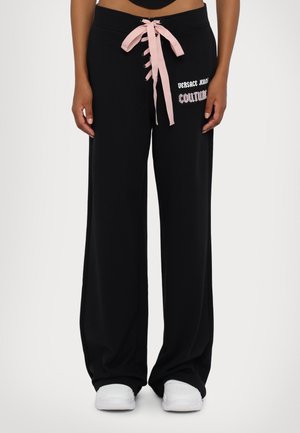 Pantaloni sportivi neri a gamba larga con un cordoncino rosa e la grafica "Versace Jeans Couture" sul lato. Tessuto morbido e vestibilità rilassata.