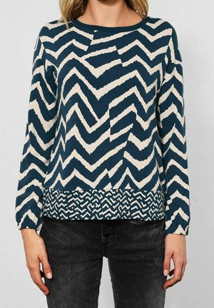 Langärmliger Pullover in Marineblau und Creme mit einem Zickzackmuster und strukturiertem Saum. Verfügt über elastische Bündchen und einen runden Halsausschnitt.
