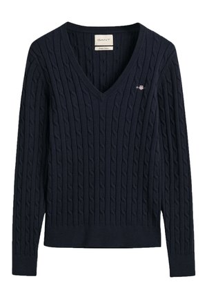 Pull en tricot bleu marine avec un col en V, présentant un motif en câble texturé. Comprend un petit logo brodé sur la poitrine.