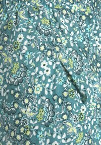 Blommönstrad tyg i teal, med gula och vita blommor. Mjuk textur med veckad midja och sidofickdetalj.