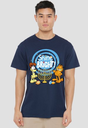 Dunkelblaue Baumwoll-T-Shirt mit einem Cartoon-Design, das zwei Charaktere und eine Menora zeigt, mit dem auffälligen Text "Shine BRIGHT!" und Stern-Akzenten.