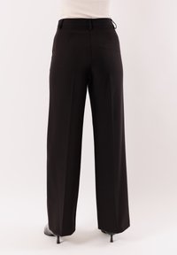 Pantaloni neri a gamba larga con una finitura liscia e strutturata, caratterizzati da una vestibilità su misura, tasche laterali e una cintura pulita.