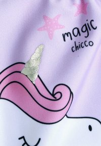 Tessuto a tema unicorno di colore viola chiaro con criniera rosa, corno argentato e contorni neri, accompagnato dal testo "magic chicco" e stelle rosa.