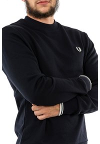 Felpa girocollo navy in cotone con polsini a coste, dotata di un logo bianco sul petto e strisce bianche ai polsini.