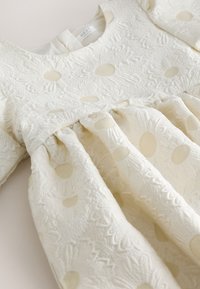Robe pour tout-petit couleur crème avec motif floral et à pois texturé, manches longues et détail taille froncée.
