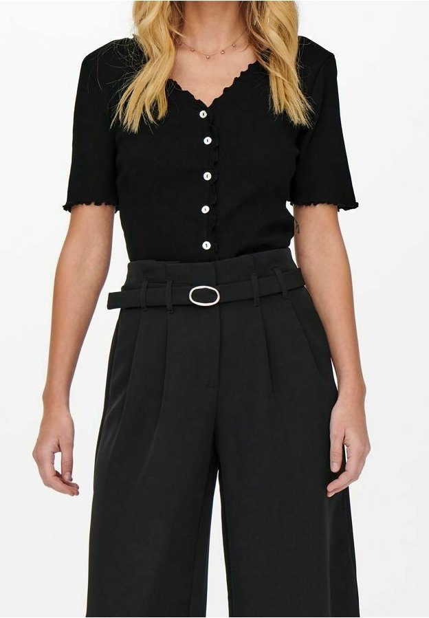Black ribbed short-sleeve top with scalloped edges and white buttons, paired with high-waisted black trousers featuring a belt with an oval buckle.
