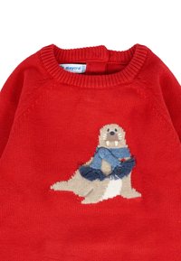 Maglione rosso lavorato a maglia con un'otter beige che indossa una sciarpa blu. Il design include un collo rotondo e polsini a costine.