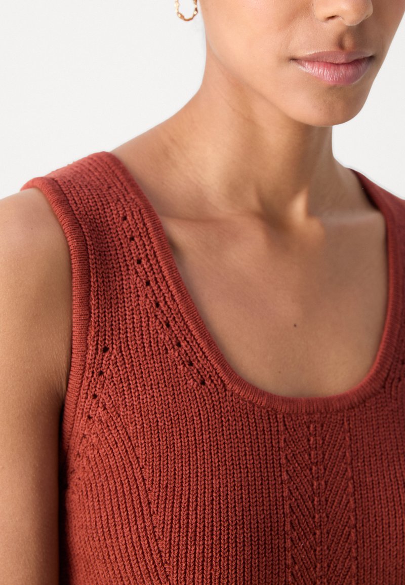 Rostfarbene gestrickte Tanktop mit weitem Ausschnitt, das über strukturierte Muster und kleine dekorative Löcher an den Schultern verfügt.
