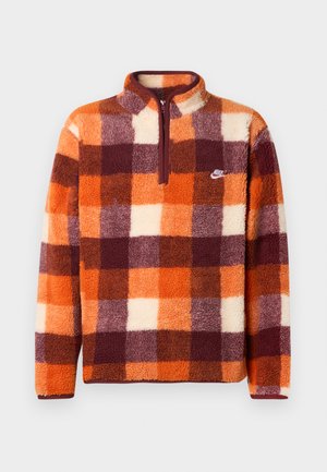 Pullover de fleece da Nike com padrão xadrez laranja, bordô e creme, com zíper de um quarto e logótipo bordado no lado esquerdo do peito.