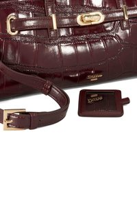 Burgundy patent leather handbag with crocodile texture, gold hardware, a detachable strap, and a matching luggage tag.