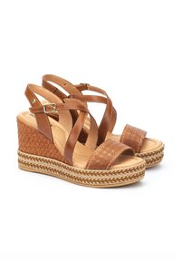 Sandalias de cuña de cuero marrón con tiras entrelazadas, textura tejida en la cuña y acentos trenzados a lo largo de la suela.