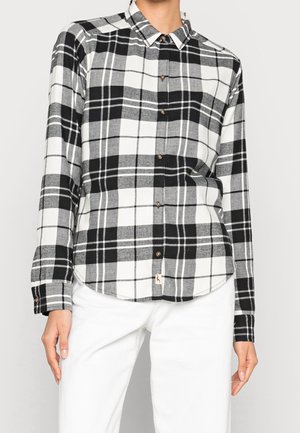 Camicia a scacchi bianca e nera con maniche lunghe, design con bottoni, orlo arrotondato e un piccolo logo in basso. Materiale in cotone.