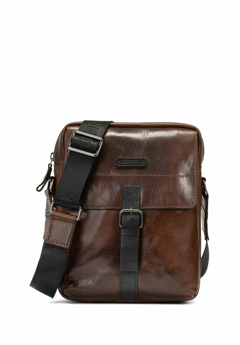 Brązowa skórzana torba na ramię o gładkiej fakturze, z czarnym regulowanym paskiem, zapięciem na klamrę z przodu oraz wytłoczonym detalem logo.