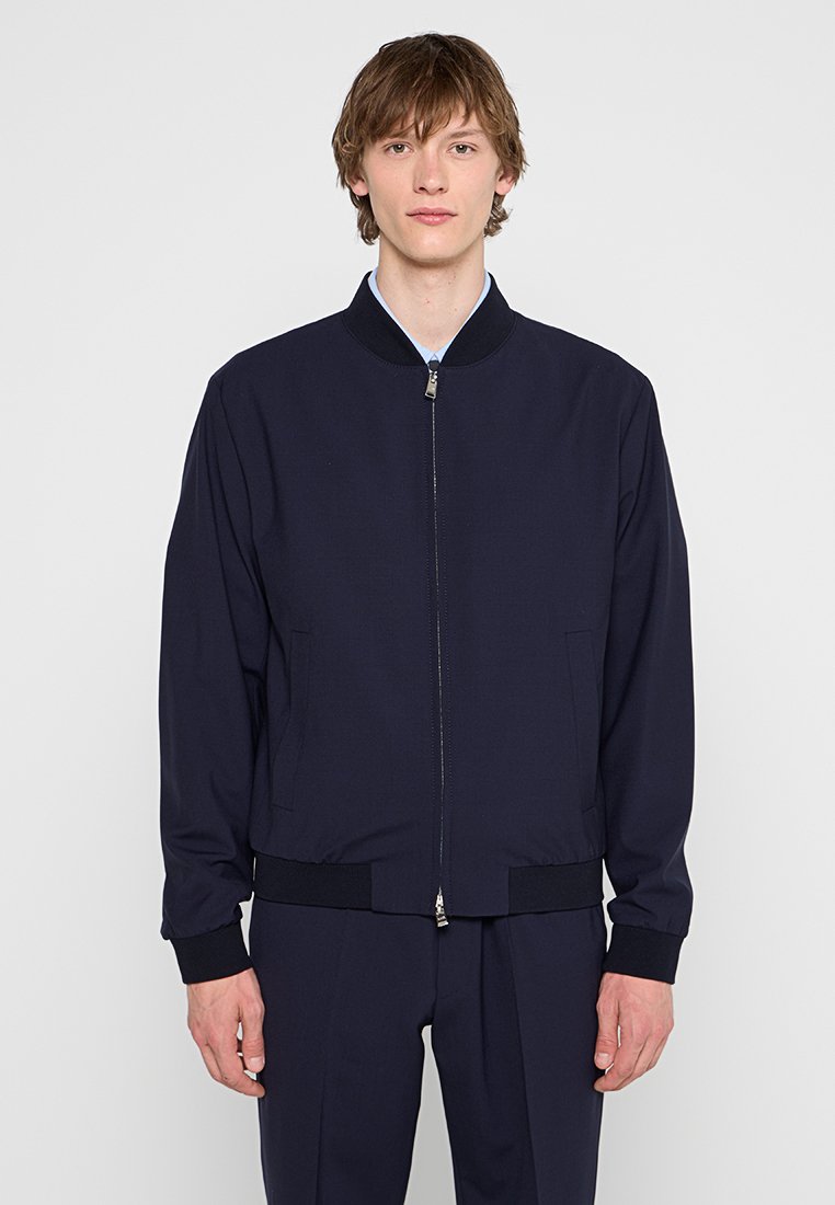 Marineblaue Bomberjacke mit Reißverschluss, gestrickten Bündchen und zwei Seitentaschen. Hergestellt aus glattem Stoff, mit einem klassischen Rippkragen.