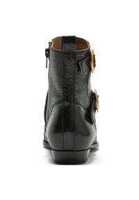 Stivaletto nero alla caviglia con finitura effetto pitone testurizzato, zip laterale, due bottoni color oro e tacco basso. Fodera interna liscia.