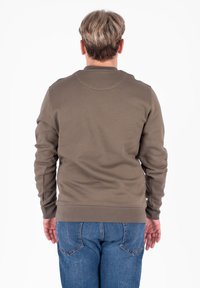 Khaki bluza z okrągłym dekoltem, ściągaczami przy mankietach i u dołu. Widok z tyłu ukazuje gładką fakturę materiału i luźny krój, połączony z niebieskimi dżinsami.