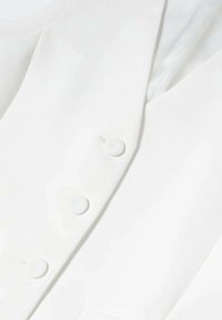 Biała marynarka dopasowana z trzema białymi guzikami z przodu, eksponowana na neutralnym tle.