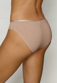 Beige Baumwoll-Hipster-Unterwäsche mit glatter Textur, ausgestattet mit einem dünnen elastischen Bund und minimalen Nahtdetails, seitlich gezeigt.