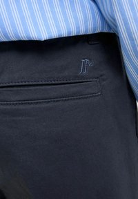 Marineblauwe broek van een zachte katoenmix, met een achterzak met subtiele stiksels en een klein geborduurd logo boven de zak.