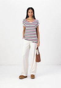 Stripet t-skjorte med kort erme og rund hals, med marineblå, rosa og hvite striper; kombinert med hvite vide bukser og brune tilbehør.