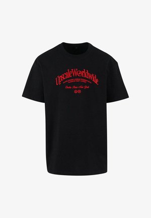 Črna bombažna majica s kratkimi rokavi, ki ima rdeče natisnjene besede "Upscale Worldwide" ter dodatne urbana-tematske fraze spodaj.