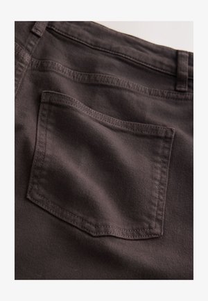 Sötét barna farmernadrág közeli kép, egyetlen megerősített varrású hátsó zsebbel, sima textúrával és klasszikus fazonú kialakítással.