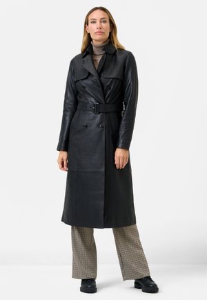 Black leather trench coat with double-breasted buttons, wide collar, detachable belt, and long sleeves, worn over checkered pants and black shoes.