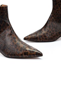 Botines de charol con estampado de leopardo en cuero marrón y negro, con punta afilada, textura lisa y un diseño elegante.