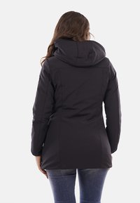 Giacca nera con cappuccio realizzata in tessuto liscio, dal design aderente, con una lunghezza che arriva appena sopra i fianchi e cuciture minime.