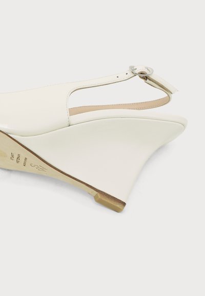 Sandale compensée blanche en cuir avec bride arrière et boucle argentée, talon haut lisse et courbé.